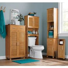 a bathroom with a toilet, cabinet and towel rack on the floor in front of it