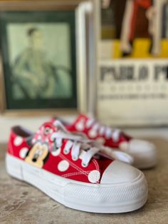 a pair of red and white sneakers sitting on top of a table next to a painting