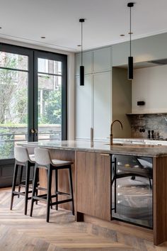 a kitchen with two bar stools next to an island and large glass doors leading outside