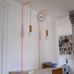 two lamps are hanging on the wall above a book shelf