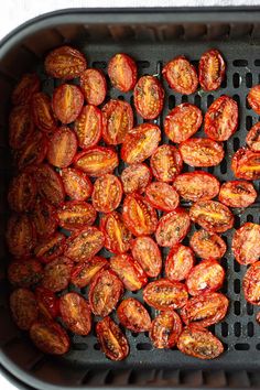 roasted tomatoes in an air fryer basket ready to be cooked for the next meal