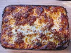 a square casserole dish with cheese and meat on it sitting on a wooden table