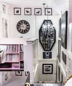 a clock mounted to the side of a wall next to a shelf filled with records