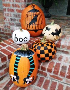 four pumpkins with painted faces and words on them