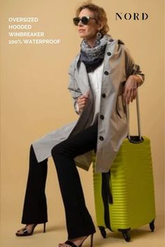 lady in ice grey rain coat, that also functions as a windbreaker, with long sleeves, reaching to the knees and with a hood, sitting on her trolley with high heels and sunglasses. Oversized Raincoat, Be Resilient, Wind Breaker, Business Outfit, Wrist Cuffs, Rain Coat, Feminine Look, Look Stylish, Business Outfits