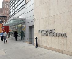 people walk past the new york law school sign on a building's front entrance