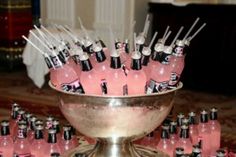 a silver bowl filled with lots of pink soda bottles next to a bunch of black and white straws