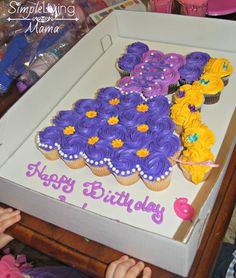 a birthday cake with purple and yellow cupcakes