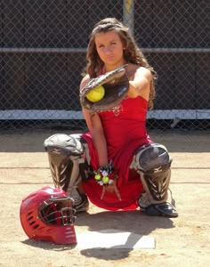 a girl in a red dress holding a softball glove and ball