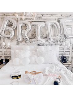 a bed with white sheets and balloons in front of a wall that says bridal