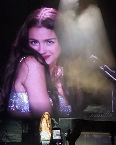 a woman standing in front of a stage with a microphone on it's side