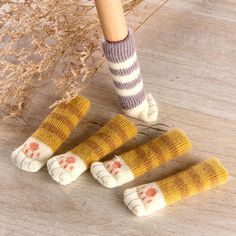 three knitted feet with socks on them sitting next to a wooden floor and an umbrella