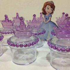 there are many glass containers with princess figurines in them on the table next to each other