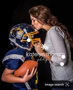 a woman kissing a young boy wearing a football helmet and holding an american football ball