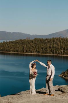 a man and woman standing on top of a cliff