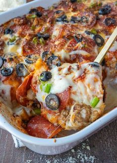 a casserole dish with cheese, olives and meat