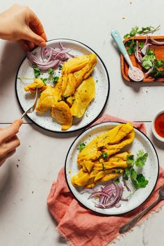 two plates filled with food on top of a white table next to utensils