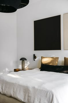 a white bed sitting in a bedroom next to a painting on the wall above it