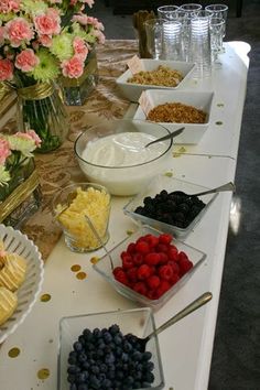 a table topped with lots of different types of foods and desserts next to vases filled with flowers