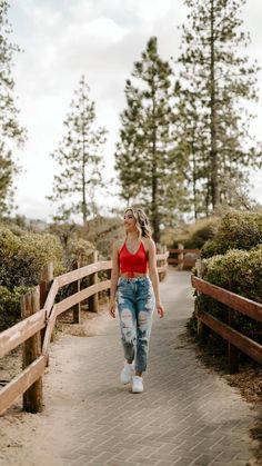 a woman walking across a wooden bridge