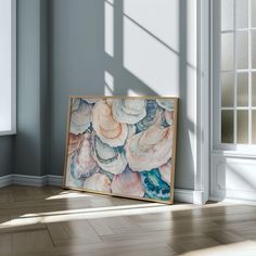 a painting is sitting on the floor next to a window with sunlight coming through it