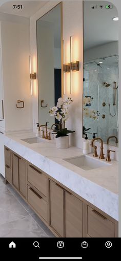 a bathroom with double sinks and large mirrors on the wall above them is illuminated by lights