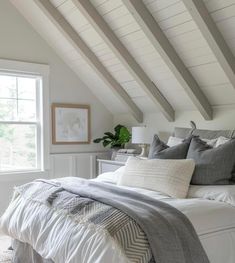 a bedroom with white and gray bedding, pillows and blankets on the bedspread