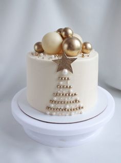 a white cake with gold ornaments on top and a star decoration on the side, sitting on a plate