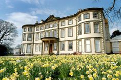 a large white building with lots of windows and flowers in front of it on a sunny day