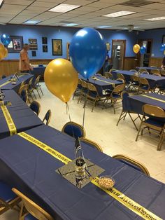 balloons and streamers are on the tables in this room for a graduation party with blue tablecloths