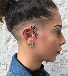 a woman with black ink on her face and behind the ear, wearing blue jeans