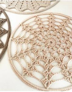 two crocheted doily are shown on a white surface, one is beige and the other is brown