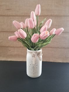 pink tulips in a white mason jar on a black countertop with burlap