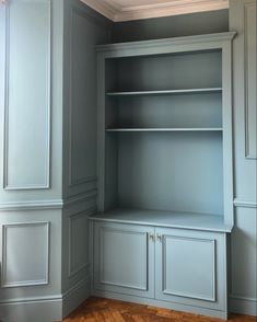 an empty room with blue painted walls and wooden floors, built - in bookshelves