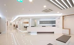 the interior of a modern office building with white walls and flooring is lit by recessed lights