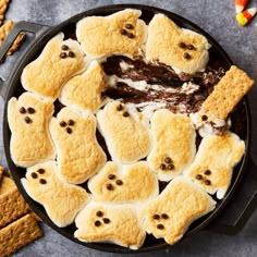 a pan filled with cookies and marshmallows in the shape of ghost faces