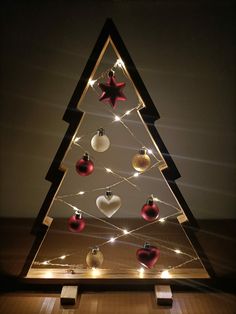 a lighted christmas tree with red and white baubles hanging from it's sides