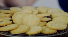 a plate full of cookies sitting on top of a wooden table next to a person