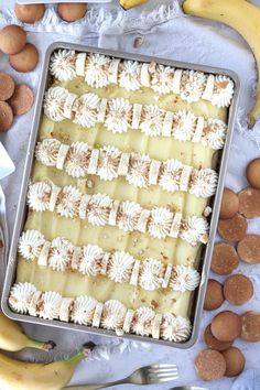 a pan filled with cake next to bananas and other dessert items on a table top