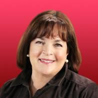 a woman smiling for the camera in front of a red background