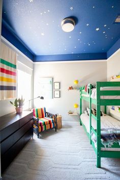 a bedroom with two bunk beds and a night sky painted on the wall above them