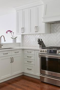 a kitchen with white cabinets and stainless steel stove top oven, wood flooring and wooden floors