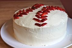 a white cake topped with strawberries on top of a wooden table