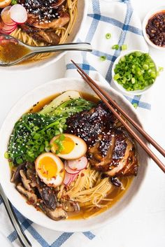 two bowls of ramen with chopsticks on the side, and an egg in the middle