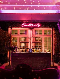 the outside of a restaurant with lights on and purple lighting shining down at the bar