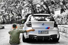 a man kneeling down next to a white car