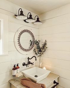 a white sink sitting under a bathroom mirror next to a wooden table with a towel on it