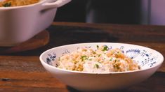 a bowl filled with food sitting on top of a wooden table next to another bowl