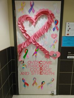 a door decorated with pink ribbon and heart shaped paper on the front, in a public restroom