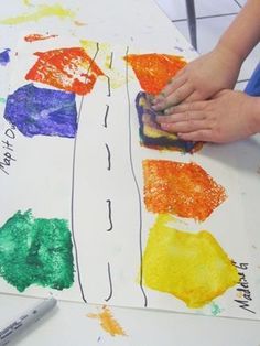 a child's hands painting on paper with crayons and watercolors